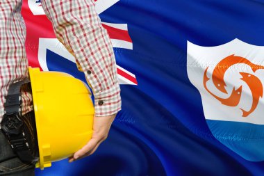 Anguillian mühendisi sarı güvenlik kask sallayarak Anguilla bayrak arka plan ile tutuyor. İnşaat ve yapı kavramı.