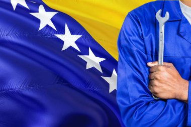 Bosnalı makinist mavi üniformalı anahtarı sallayarak Bosna Hersek bayrağı arka planı tutuyor. Çapraz silah teknisyen.