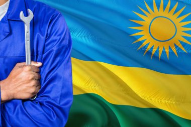 Mavi üniformalı Ruanda tamirci anahtarı sallayarak Ruanda bayrak arka planı tutuyor. Çapraz silah teknisyen.