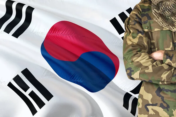 Crossed arms South Korean soldier with national waving flag on background - South Korea Military theme.
