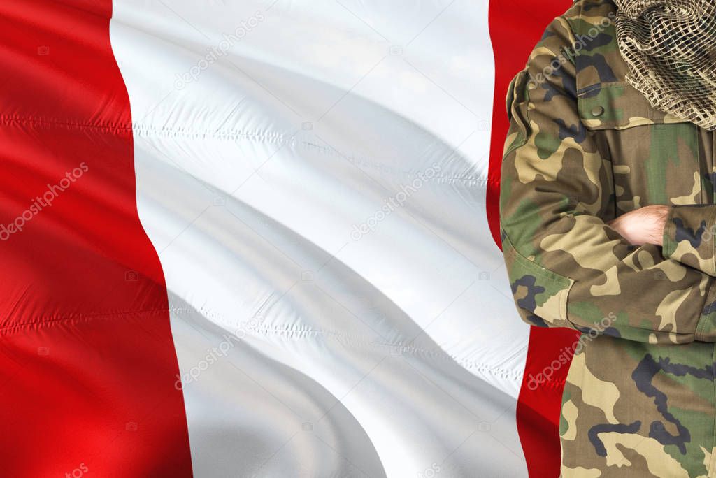 Crossed arms Peruvian soldier with national waving flag on background - Peru Military theme.