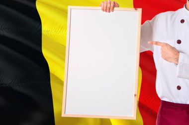 Belçikalı Şef boş beyaz tahta menü Belçika bayrağı arka üzerinde tutarak. Metin için Tekdüzen işaret yer giyen yemek.