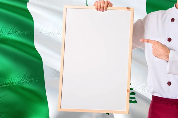 Chef holding blank whiteboard menu on Norfolk Island flag background. Cook wearing uniform pointing space for text.