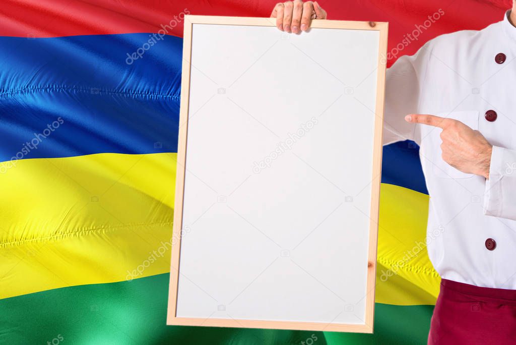 Mauritian Chef holding blank whiteboard menu on Mauritius flag background. Cook wearing uniform pointing space for text.