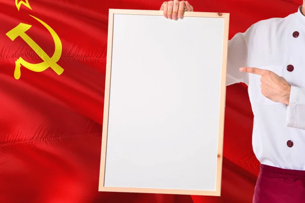 ソビエト連邦の旗の背景の空白のホワイト ボード メニューを保持しているシェフ 本文制服ポインティング領域を着て調理します — ストック写真