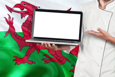 Galce laptop boş ekran ile Galler bayrak arka planda tutan Şef. Giyen üniforma ve işaretleme laptop kopya alanı için cook.