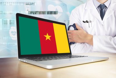 Kamerun teknik Tema sağlık sisteminde. Kamerunlu bayrak bilgisayar ekranında. Hastanede stetoskop ile ayakta doktor. Cryptocurrency ve Blockchain kavramı.
