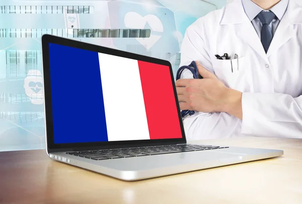 France healthcare system in tech theme. French flag on computer screen. Doctor standing with stethoscope in hospital. Cryptocurrency and Blockchain concept.