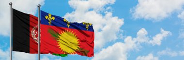 Afganistan ve Guadeloupe bayrağı birlikte beyaz bulutlu mavi gökyüzüne karşı rüzgarda sallayarak. Diplomasi kavramı, uluslararası ilişkiler.