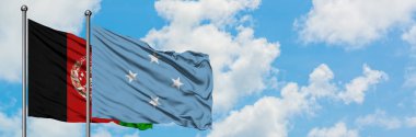 Afganistan ve Mikronezya bayrağı birlikte beyaz bulutlu mavi gökyüzüne karşı rüzgarda sallayarak. Diplomasi kavramı, uluslararası ilişkiler.