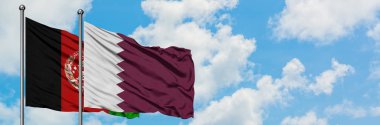 Afganistan ve Katar bayrağı birlikte beyaz bulutlu mavi gökyüzüne karşı rüzgarsal sallayarak. Diplomasi kavramı, uluslararası ilişkiler.