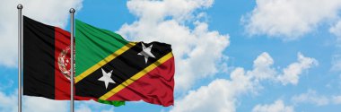 Afganistan ve Saint Kitts ve Nevis bayrağı birlikte beyaz bulutlu mavi gökyüzüne karşı rüzgarda sallayarak. Diplomasi kavramı, uluslararası ilişkiler.