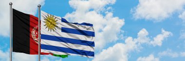 Afganistan ve Uruguay bayrağı birlikte beyaz bulutlu mavi gökyüzüne karşı rüzgarda sallayarak. Diplomasi kavramı, uluslararası ilişkiler.