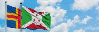Aland Adaları ve Burundi bayrağı birlikte beyaz bulutlu mavi gökyüzüne karşı rüzgarda sallayarak. Diplomasi kavramı, uluslararası ilişkiler.