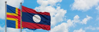 Aland Adaları ve Laos bayrağı birlikte beyaz bulutlu mavi gökyüzüne karşı rüzgarda sallayarak. Diplomasi kavramı, uluslararası ilişkiler.