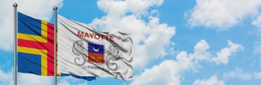 Aland Adaları ve Mayotte bayrağı birlikte beyaz bulutlu mavi gökyüzüne karşı rüzgarda sallayarak. Diplomasi kavramı, uluslararası ilişkiler.