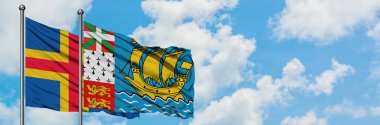 Aland Adaları ve Saint Pierre ve Miquelon bayrağı birlikte beyaz bulutlu mavi gökyüzüne karşı rüzgarda sallayarak. Diplomasi kavramı, uluslararası ilişkiler.