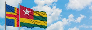Aland Adaları ve Togo bayrağı birlikte beyaz bulutlu mavi gökyüzüne karşı rüzgarda sallayarak. Diplomasi kavramı, uluslararası ilişkiler.