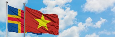 Aland Adaları ve Vietnam bayrağı birlikte beyaz bulutlu mavi gökyüzüne karşı rüzgarda sallayarak. Diplomasi kavramı, uluslararası ilişkiler.