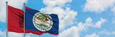 Arnavutluk ve Belize bayrağı birlikte beyaz bulutlu mavi gökyüzüne karşı rüzgarda sallayarak. Diplomasi kavramı, uluslararası ilişkiler.