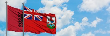 Arnavutluk ve Bermuda bayrağı birlikte beyaz bulutlu mavi gökyüzüne karşı rüzgarda sallayarak. Diplomasi kavramı, uluslararası ilişkiler.