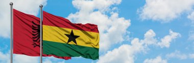 Arnavutluk ve Gana bayrağı birlikte beyaz bulutlu mavi gökyüzüne karşı rüzgarda sallayarak. Diplomasi kavramı, uluslararası ilişkiler.