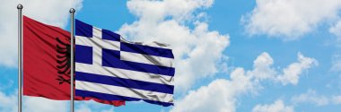 Arnavutluk ve Yunanistan bayrağı birlikte beyaz bulutlu mavi gökyüzüne karşı rüzgarda sallayarak. Diplomasi kavramı, uluslararası ilişkiler.