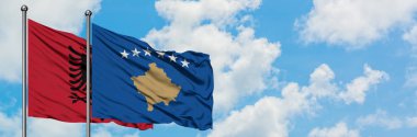 Arnavutluk ve Kosova bayrağı birlikte beyaz bulutlu mavi gökyüzüne karşı rüzgarda sallayarak. Diplomasi kavramı, uluslararası ilişkiler.