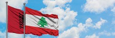 Arnavutluk ve Lübnan bayrağı birlikte beyaz bulutlu mavi gökyüzüne karşı rüzgarda sallayarak. Diplomasi kavramı, uluslararası ilişkiler.