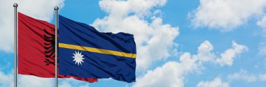 Arnavutluk ve Nauru bayrağı birlikte beyaz bulutlu mavi gökyüzüne karşı rüzgarda sallayarak. Diplomasi kavramı, uluslararası ilişkiler.