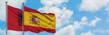 Arnavutluk ve İspanya bayrağı birlikte beyaz bulutlu mavi gökyüzüne karşı rüzgarsal sallayarak. Diplomasi kavramı, uluslararası ilişkiler.