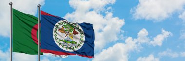 Cezayir ve Belize bayrağı birlikte beyaz bulutlu mavi gökyüzüne karşı rüzgarda sallayarak. Diplomasi kavramı, uluslararası ilişkiler.