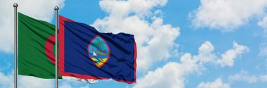 Cezayir ve Guam bayrağı birlikte beyaz bulutlu mavi gökyüzüne karşı rüzgarda sallayarak. Diplomasi kavramı, uluslararası ilişkiler.