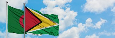 Cezayir ve Guyana bayrağı birlikte beyaz bulutlu mavi gökyüzüne karşı rüzgarda sallayarak. Diplomasi kavramı, uluslararası ilişkiler.