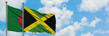 Cezayir ve Jamaika bayrağı birlikte beyaz bulutlu mavi gökyüzüne karşı rüzgarda sallayarak. Diplomasi kavramı, uluslararası ilişkiler.