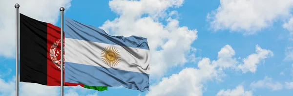 Bandera de Afganistán y Argentina ondeando en el viento contra el cielo azul nublado blanco juntos. Concepto diplomático, relaciones internacionales . — Foto de Stock
