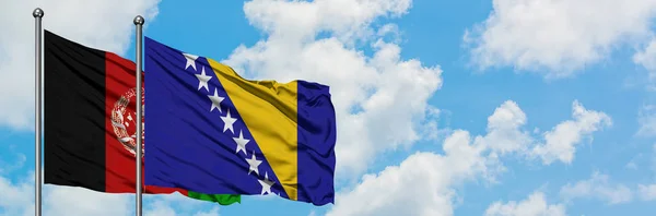 Drapeau de l'Afghanistan et de la Bosnie-Herzégovine agitant dans le vent contre le ciel bleu nuageux blanc ensemble. Concept de diplomatie, relations internationales . — Photo