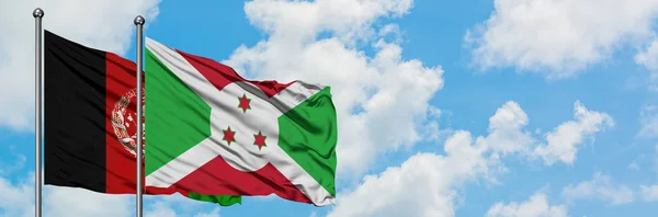 Bandera de Afganistán y Burundi ondeando en el viento contra el cielo azul nublado blanco juntos. Concepto diplomático, relaciones internacionales . — Foto de Stock