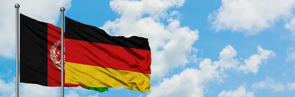 Afghanistan e Germania sventolano bandiera nel vento contro bianco cielo blu nuvoloso insieme. Concetto di diplomazia, relazioni internazionali . — Foto Stock