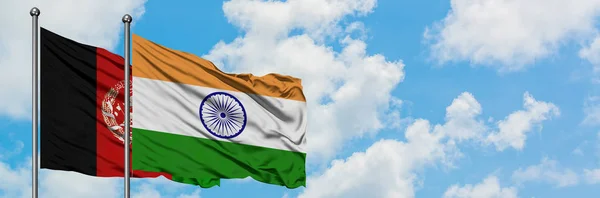 Bandera de Afganistán e India ondeando en el viento contra el cielo azul nublado blanco juntos. Concepto diplomático, relaciones internacionales . — Foto de Stock