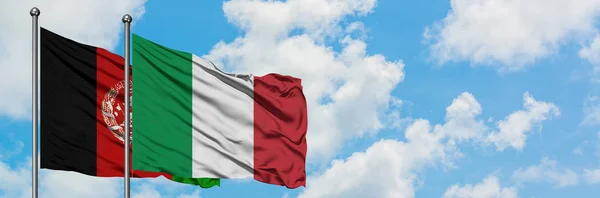 Bandera de Afganistán e Italia ondeando en el viento contra el cielo azul nublado blanco juntos. Concepto diplomático, relaciones internacionales . — Foto de Stock