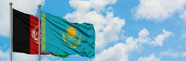 Bandera de Afganistán y Kazajstán ondeando en el viento contra el cielo azul nublado blanco juntos. Concepto diplomático, relaciones internacionales . — Foto de Stock
