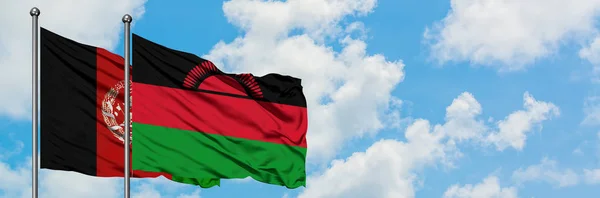 Bandera de Afganistán y Malawi ondeando en el viento contra el cielo azul nublado blanco juntos. Concepto diplomático, relaciones internacionales . — Foto de Stock