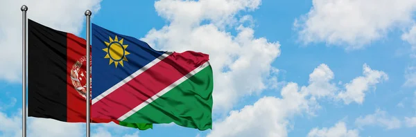 Drapeau de l'Afghanistan et de la Namibie agitant dans le vent contre ciel bleu nuageux blanc ensemble. Concept de diplomatie, relations internationales . — Photo