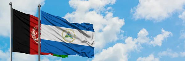 Afghanistans und Nicaraguas Flagge weht gemeinsam im Wind vor dem wolkenverhangenen blauen Himmel. Diplomatie-Konzept, internationale Beziehungen. — Stockfoto