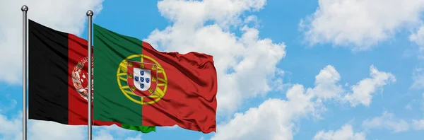 Bandeira do Afeganistão e de Portugal agitando no vento contra o céu azul nublado branco juntos. Conceito de diplomacia, relações internacionais . — Fotografia de Stock