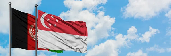Bandera de Afganistán y Singapur ondeando en el viento contra el cielo azul nublado blanco juntos. Concepto diplomático, relaciones internacionales . — Foto de Stock