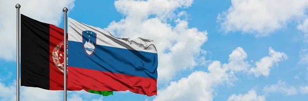 Afghanistan and Slovenia flag waving in the wind against white cloudy blue sky together. Diplomacy concept, international relations.