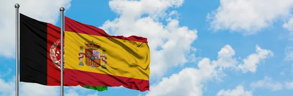 Afghanistan e Spagna sventolano bandiera nel vento contro bianco cielo blu nuvoloso insieme. Concetto di diplomazia, relazioni internazionali . — Foto Stock