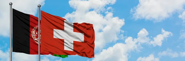 Afghanistan och Schweiz flagga vinka i vinden mot vit grumlig blå himmel tillsammans. Diplomatisk koncept, internationella relationer. — Stockfoto